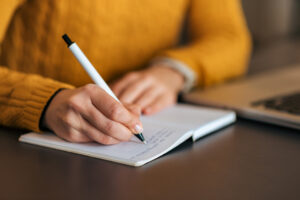 Closeup of Writer with Pen and Diary. Hero image for Writer For Hire® Pat Kramer